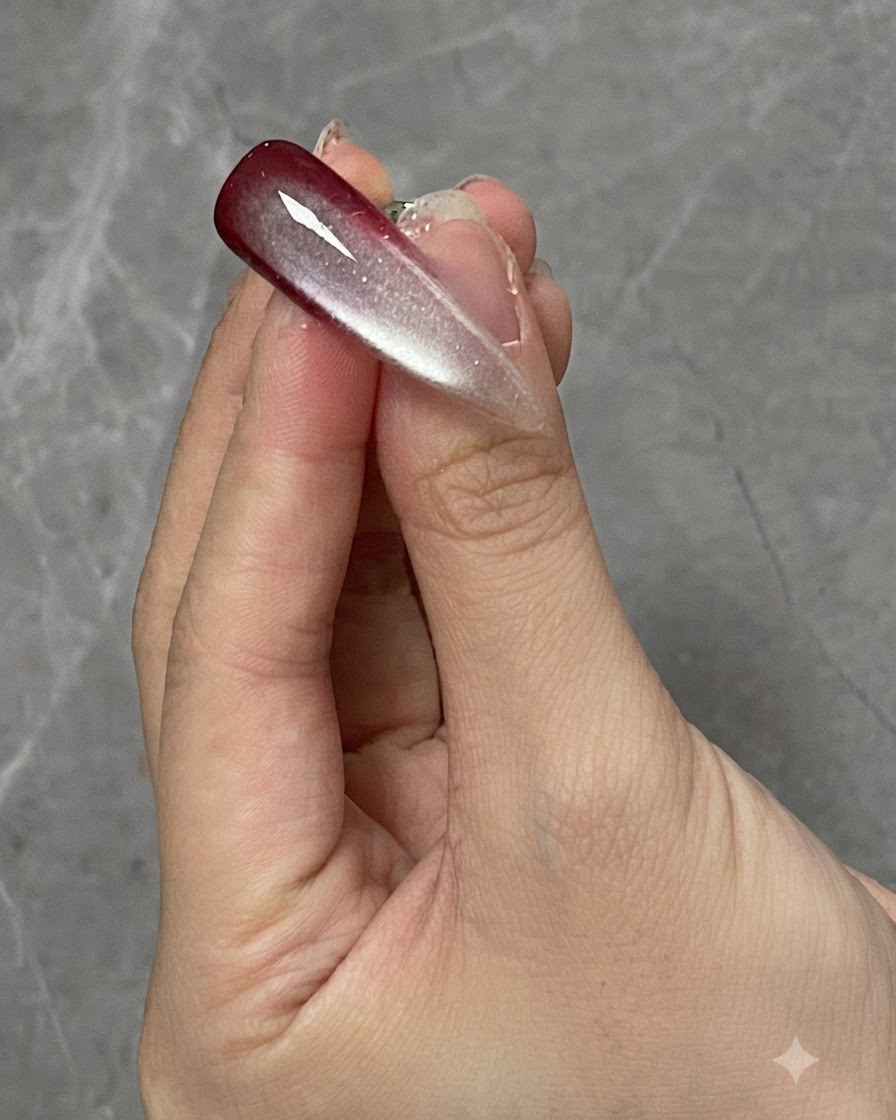 Ein Finger mit ausgehärtetem Farbverlauf und Cat-Eye-Nageldesign unter einer Aushärtungslampe positioniert.