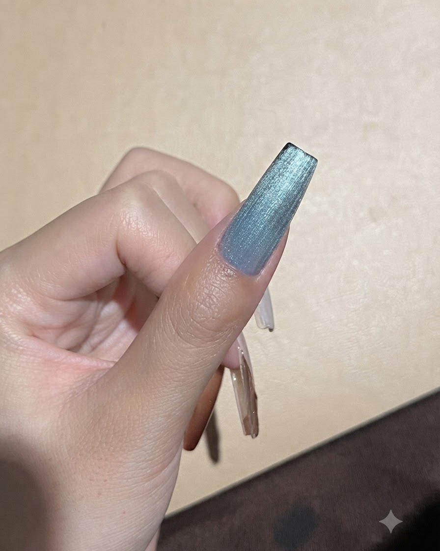 Un imán fuerte sostenido cerca de una uña de gel azul de ojo de gato para afinar la línea de reflejo de luz.