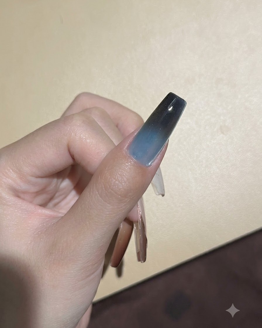 Una esponja aplicando pigmento oscuro a toquecitos en el borde superior de una uña de gel para profundizar la transición ombré.