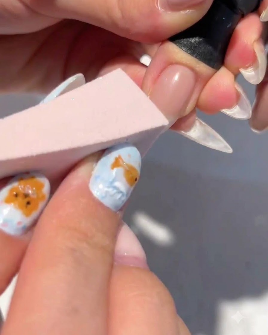 Una esponja de maquillaje aplicando toques de gel blanco en la punta de una uña para formar un degradado.