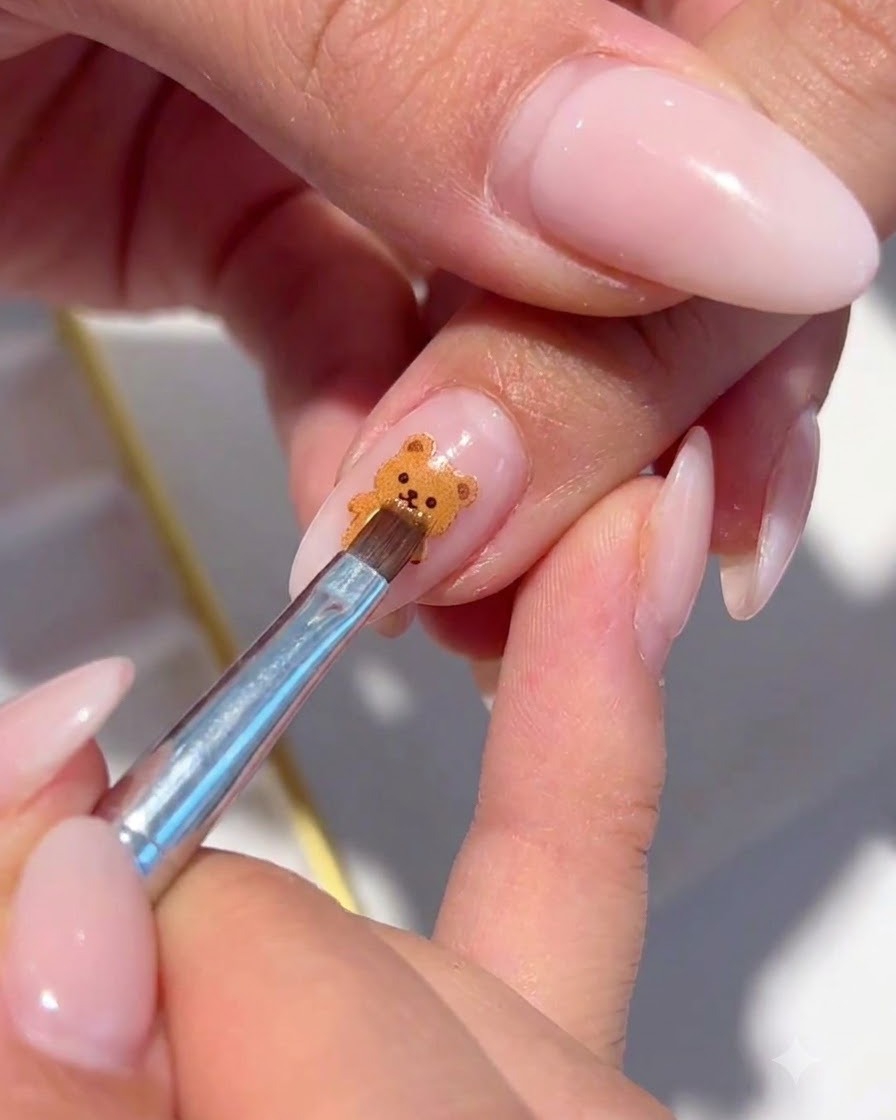 Un pincel fino colocando escamas de brillo iridiscente alrededor del arte de uñas floral pintado.