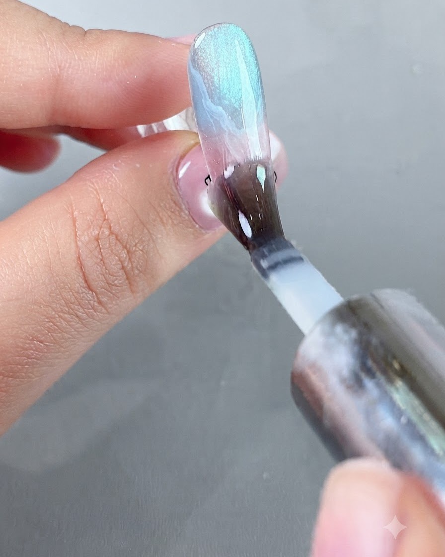 Un pincel aplicando una capa suave de top coat protector aislante de polvo sobre la superficie de la uña decorada.