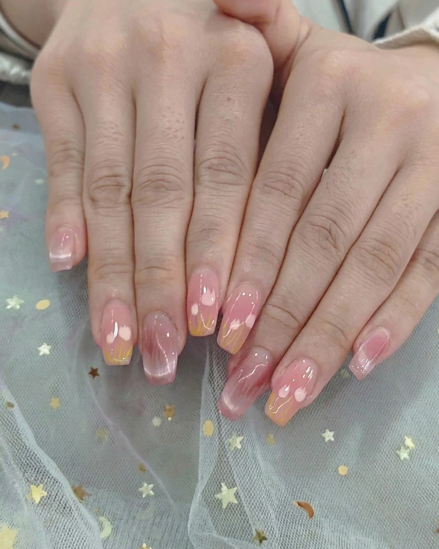 Un pincel ombre difuminando suavemente esmalte de gel rosa y amarillo en el centro de la uña.