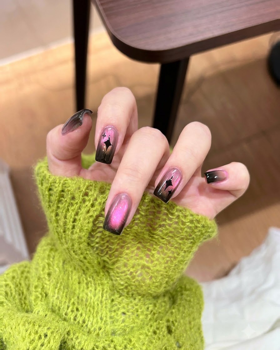 Aplicando un toque concentrado de esmalte de gel negro oscuro en la punta de una uña con degradado.