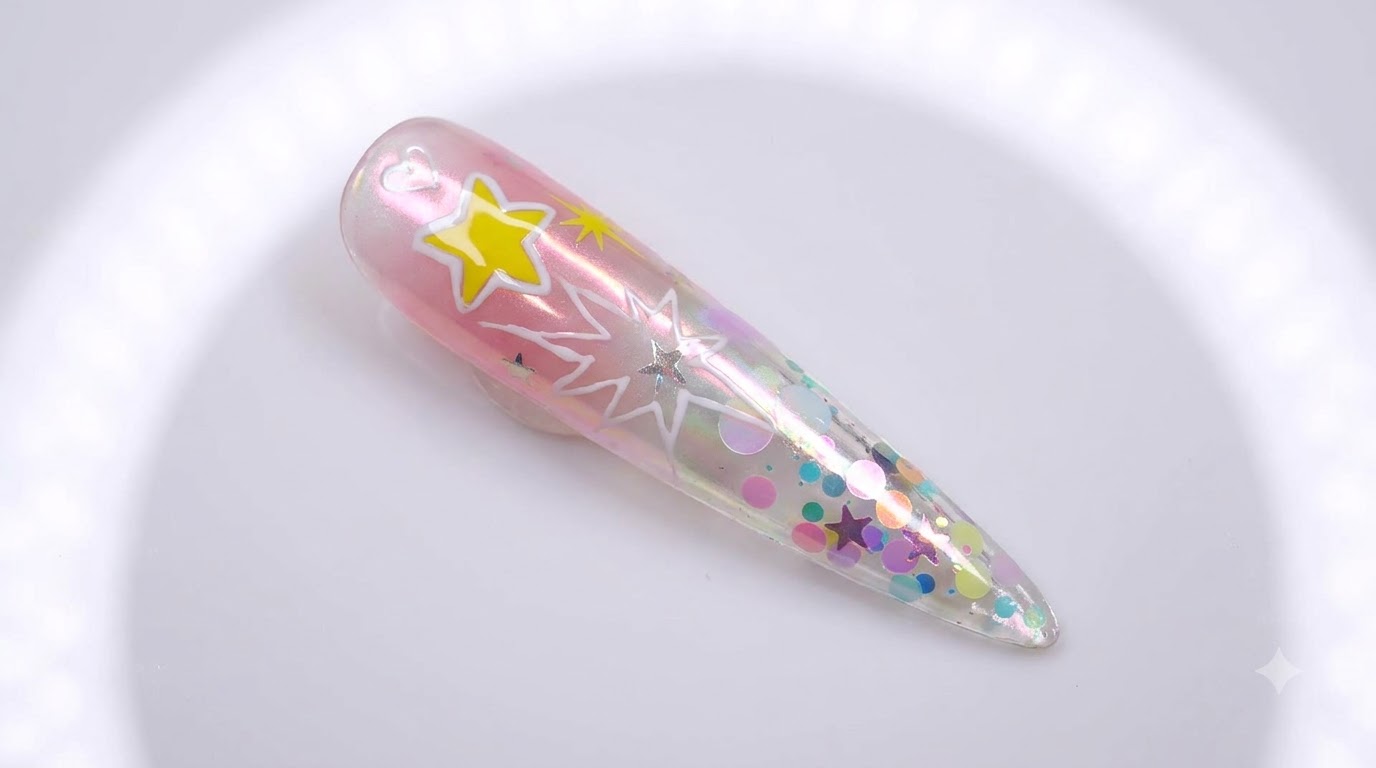 Uña stiletto larga transparente con degradado rosa, acabado cromado aurora, lentejuelas incrustadas y estrellas de explosión blancas dibujadas a mano.