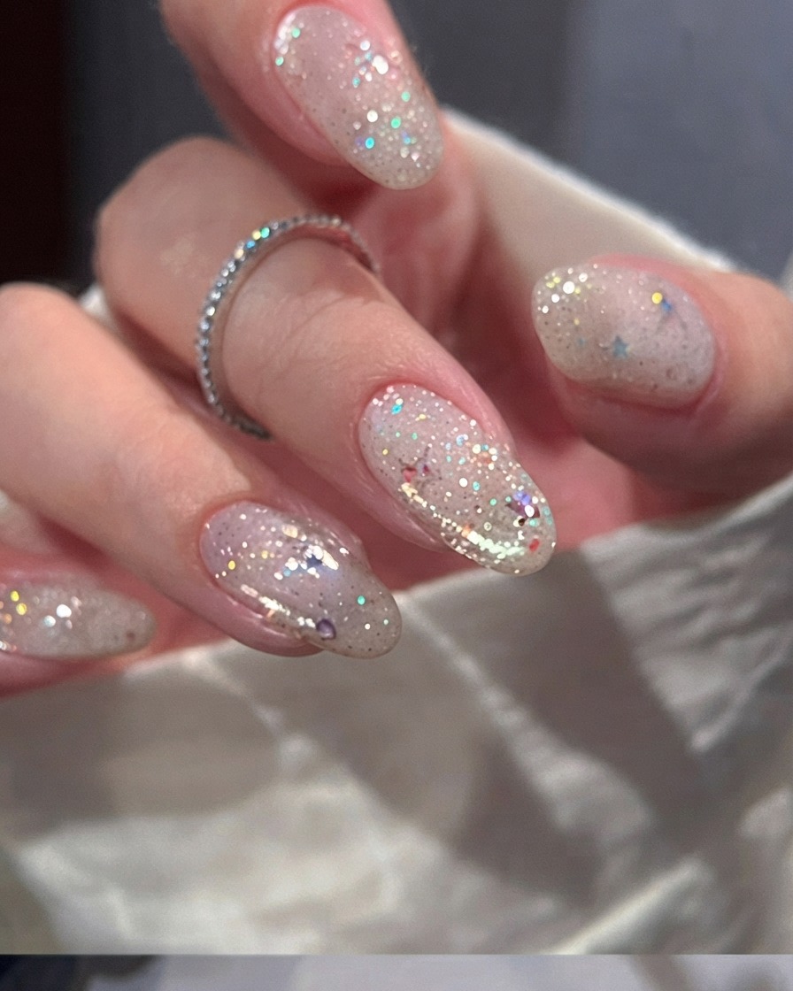 Un pincel aplicando una capa suave de esmalte en gel rosa nude sobre una uña natural.