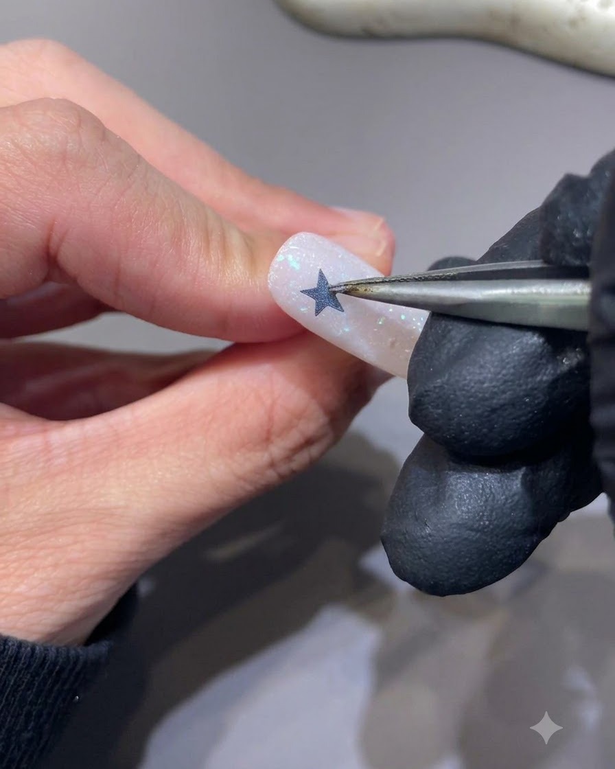 Unas pinzas despegando una pegatina de estrella de la uña para revelar una silueta de estrella hueca.