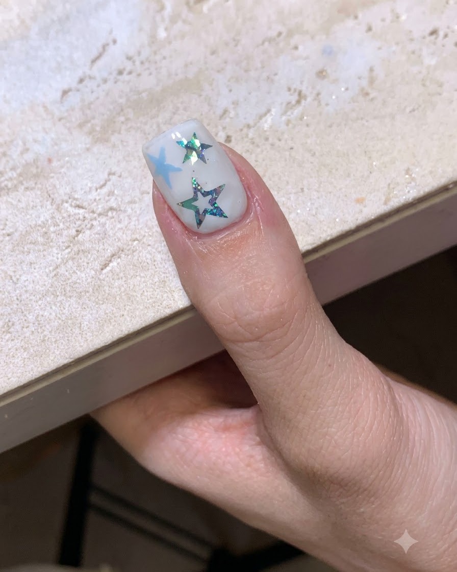 Una manicura temática de estrellas completa curándose bajo una lámpara de uñas.