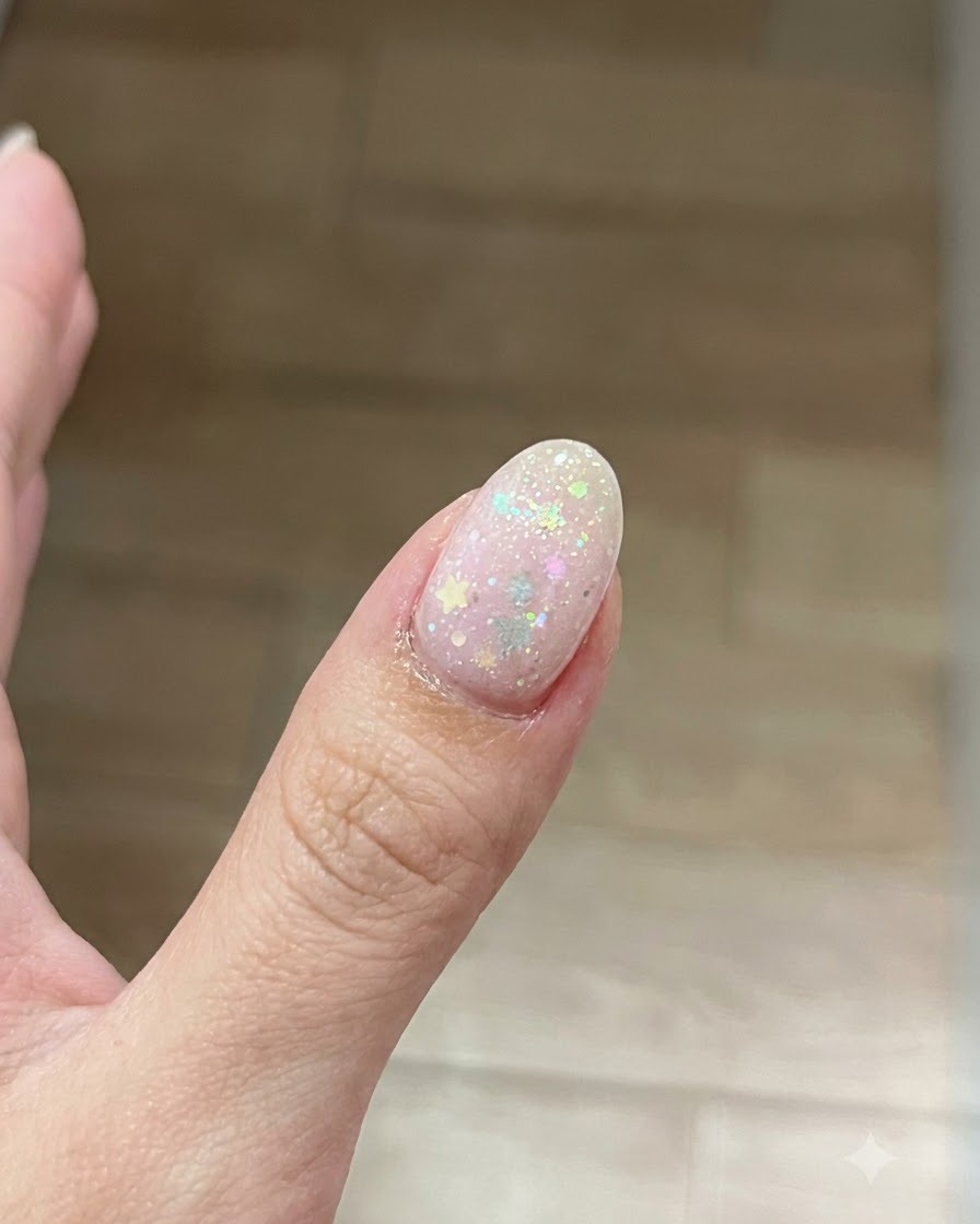 Un pincel aplicando una fina capa transparente de gel base sobre la superficie de una uña preparada.