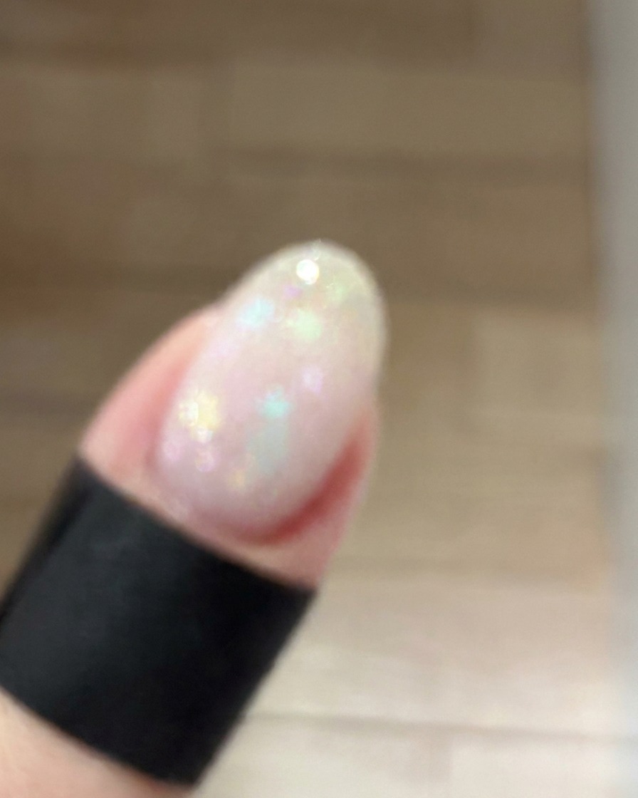 Una pequeña esponja de maquillaje aplicando a toquecitos un gel rosa oscuro en el centro de una uña para crear un suave degradado blush.