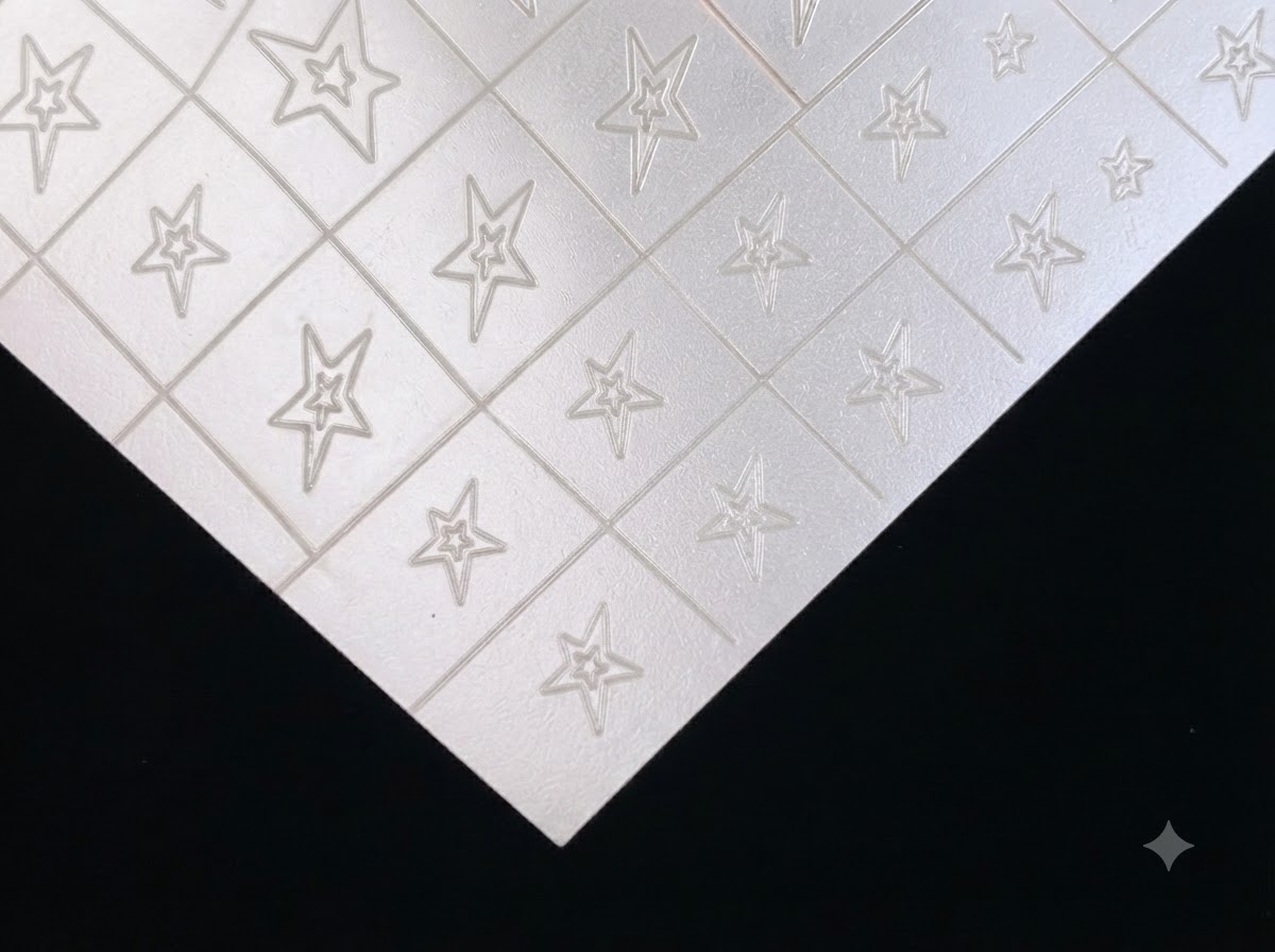 Una hoja de pegatinas de nail art con estrellas huecas transparentes y plateadas sobre un fondo oscuro.