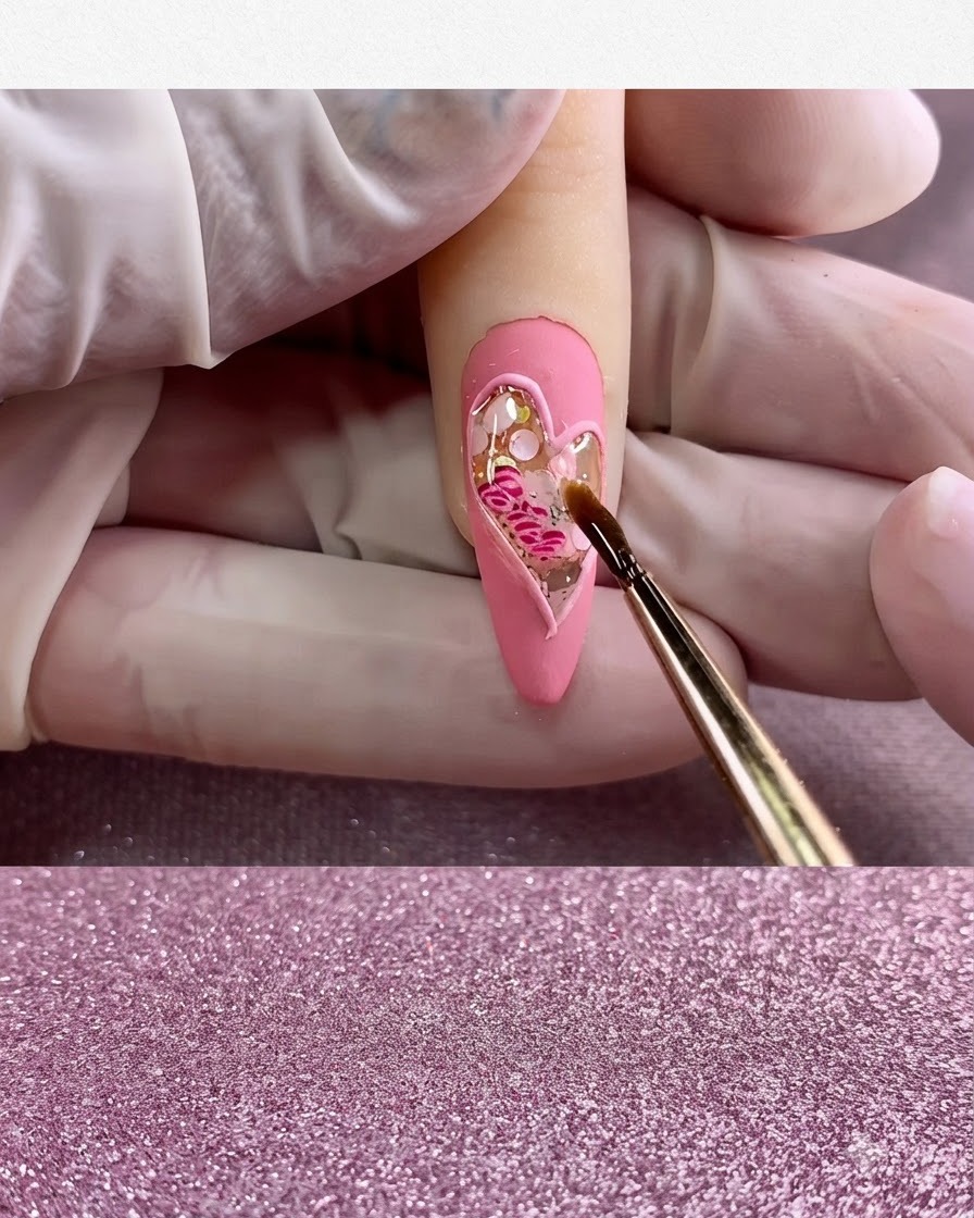 Un pincel fino aplicando top coat brillante transparente exclusivamente dentro de la figura del corazón.