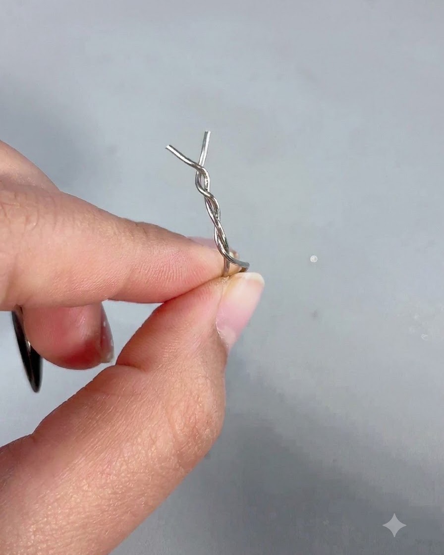 Una mano sosteniendo una varita magnética con una horquilla metálica torcida unida a su punta.