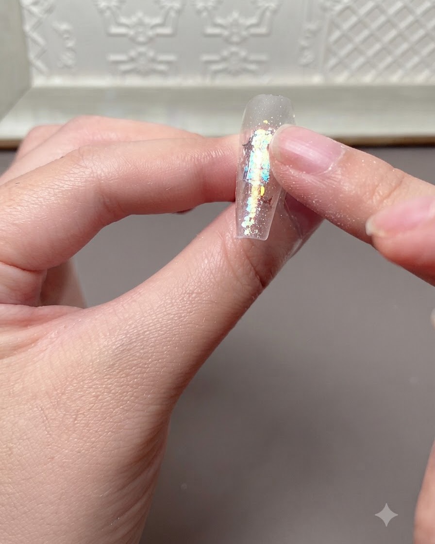 Un dedo presionando o comprobando ligeramente la superficie de una extensión de uña curada tras haber estado bajo una lámpara UV o LED.