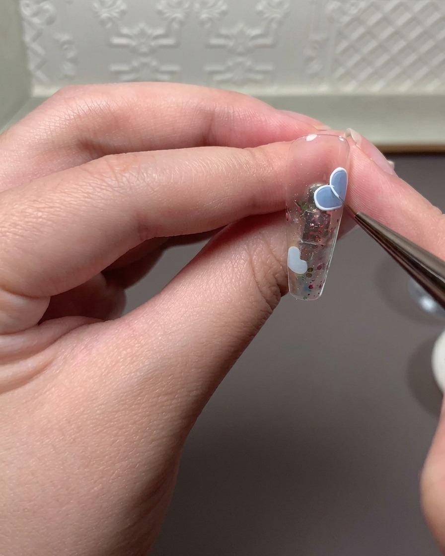 Un pincel fino aplicando una mezcla de gel en relieve y gel de dibujo blanco para trazar el contorno de un corazón.