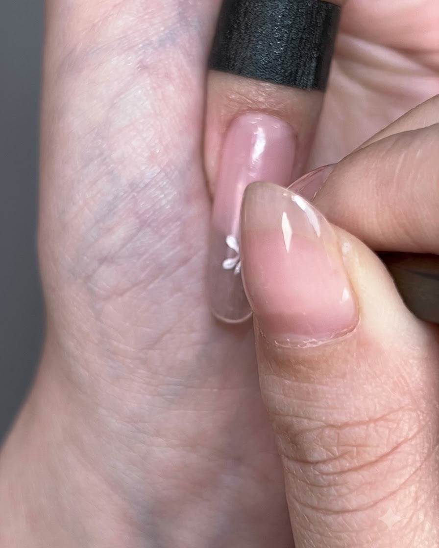 Primer plano de una flor pintada de blanco que se forma sobre la superficie de la uña.