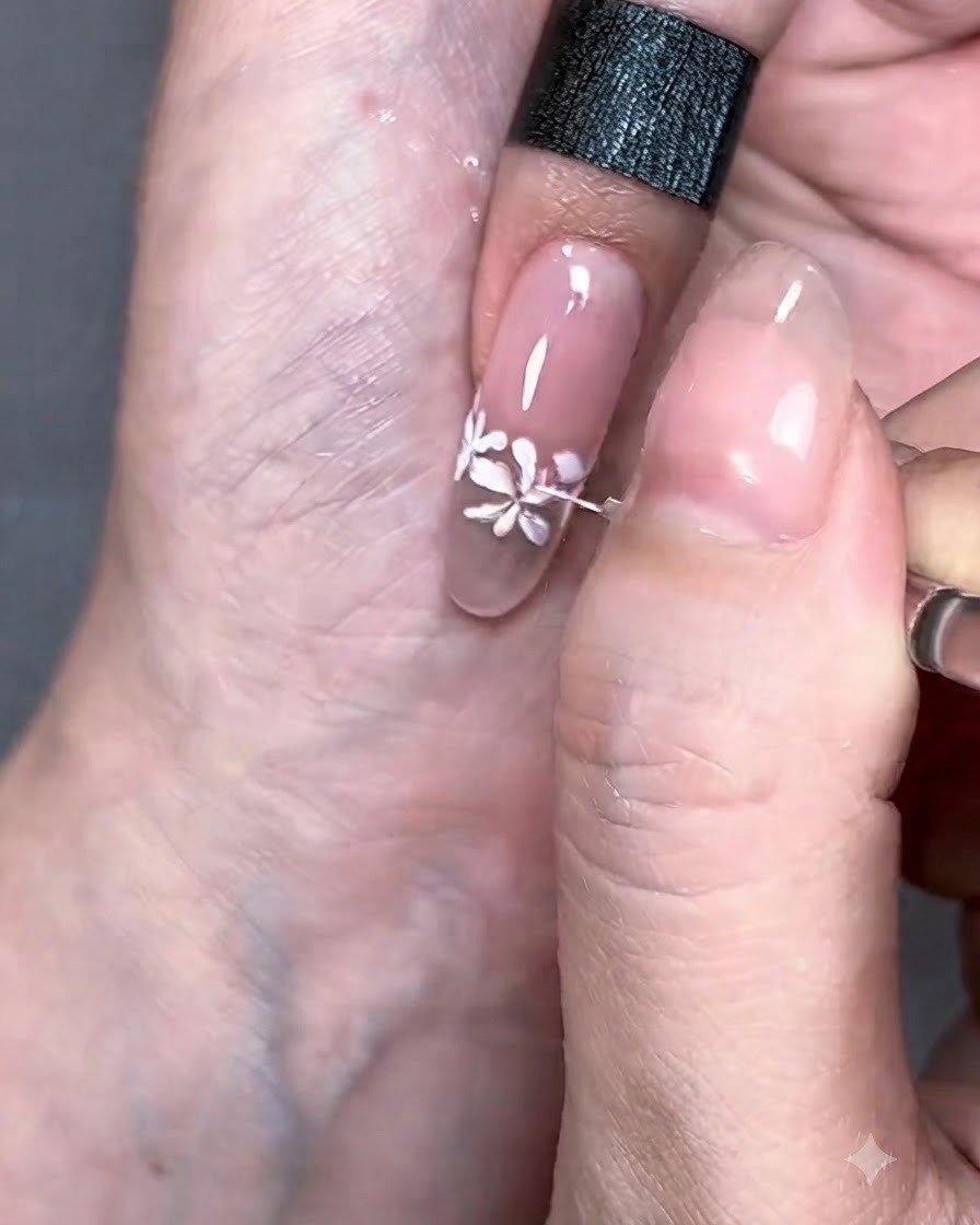 Pincel delineador fino trazando líneas blancas delicadas que se extienden desde las flores pintadas.