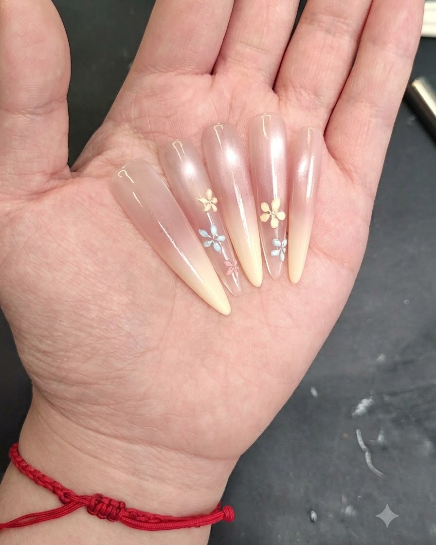 Un primer plano de una uña mostrando pétalos adicionales siendo dibujados para terminar un diseño de flor pequeña.
