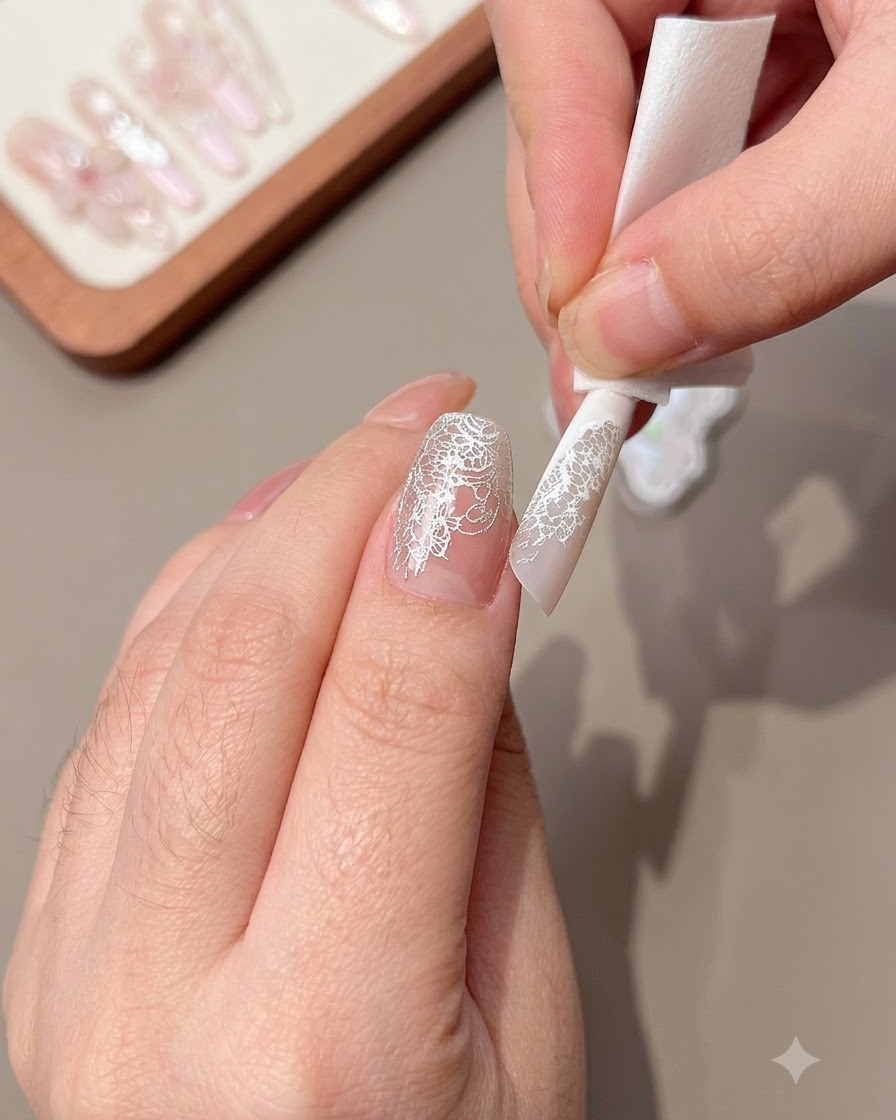 Primer plano de una mano usando una toallita para limpiar el exceso de patrón de encaje en el borde de una uña.