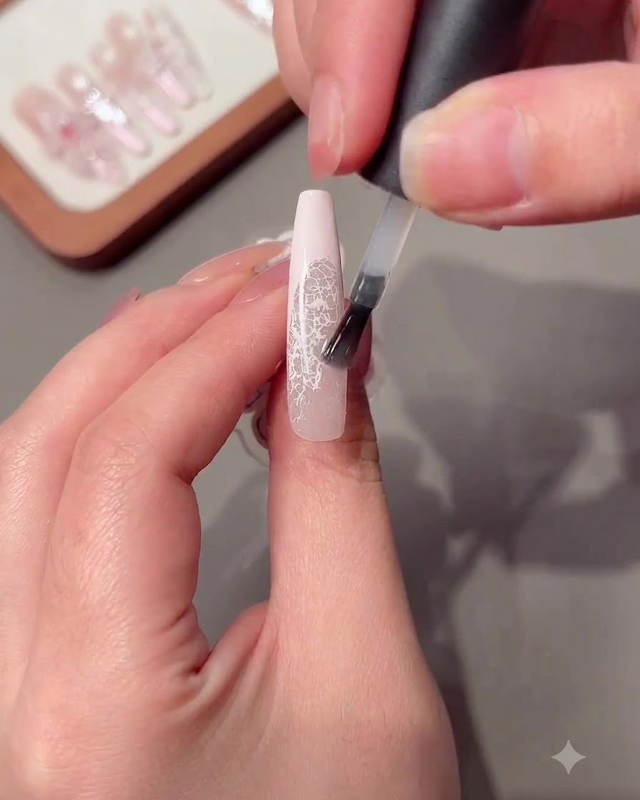 Un pincel aplicando una capa de gel constructor transparente sobre una uña larga.