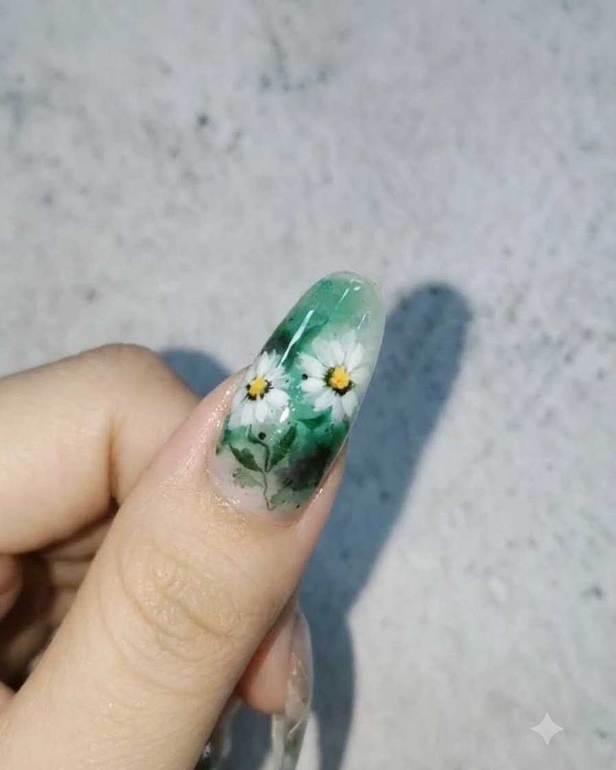Un diseño de uñas terminado que presenta margaritas blancas y hojas sobre un fondo verde con gotas de agua 3D brillantes.
