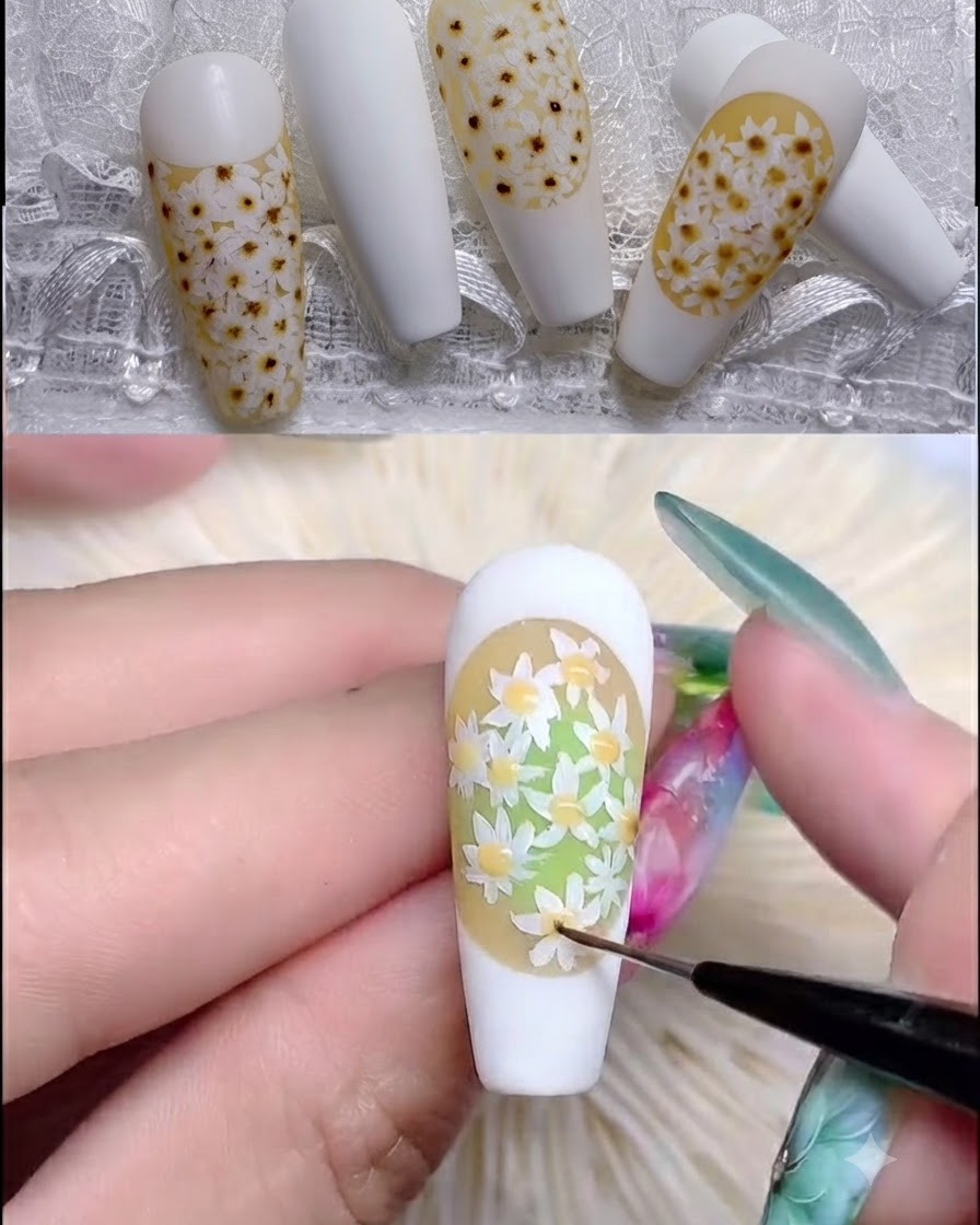 Un pincel de uñas aplicando top coat rubber transparente sobre un diseño de margaritas con textura.