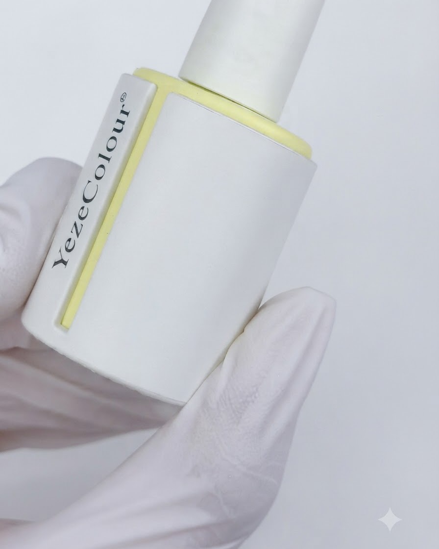 Un frasco de top coat mate terciopelo etiquetado como YezeColour sostenido en una mano con guantes.