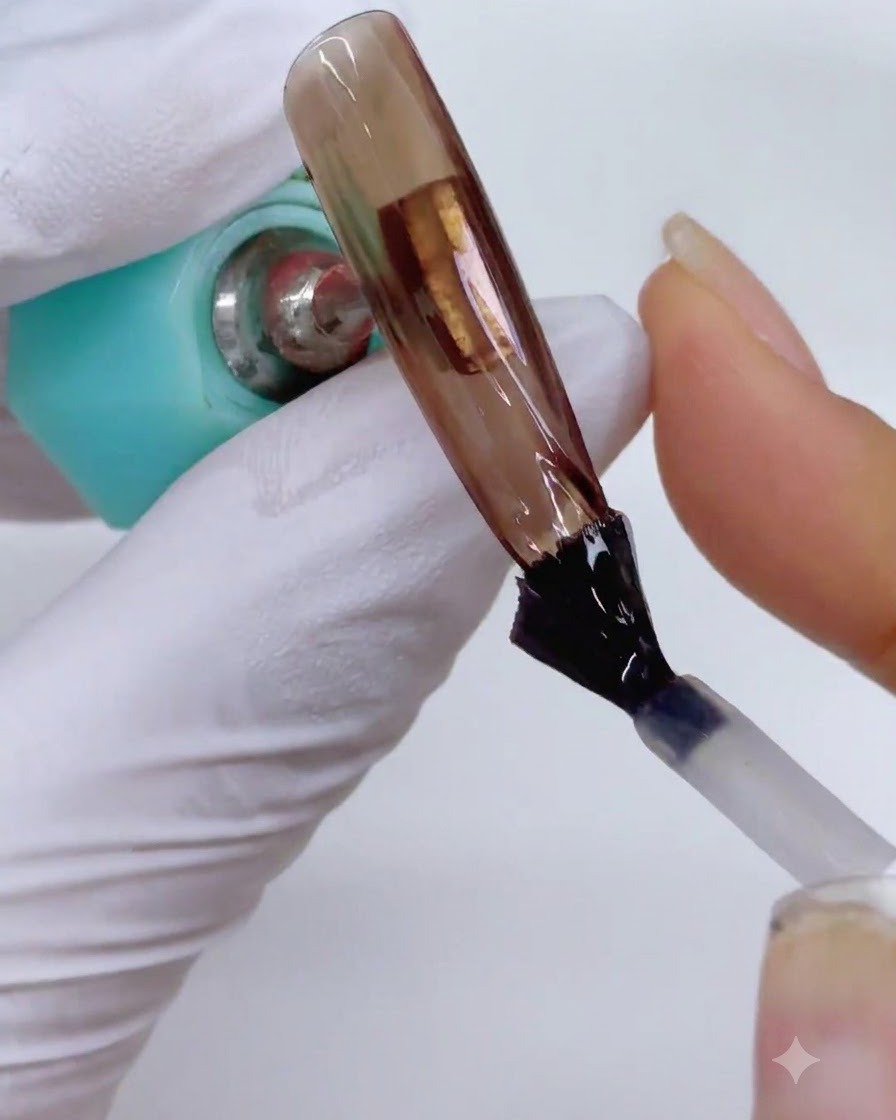 Una extensión de uña siendo colocada cerca de una lámpara de curado para fijar la capa de top coat mate.