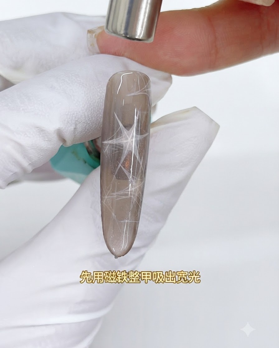 Un imán cilíndrico flotando sobre una uña cat-eye marrón para extraer una banda de luz reflectante ancha.