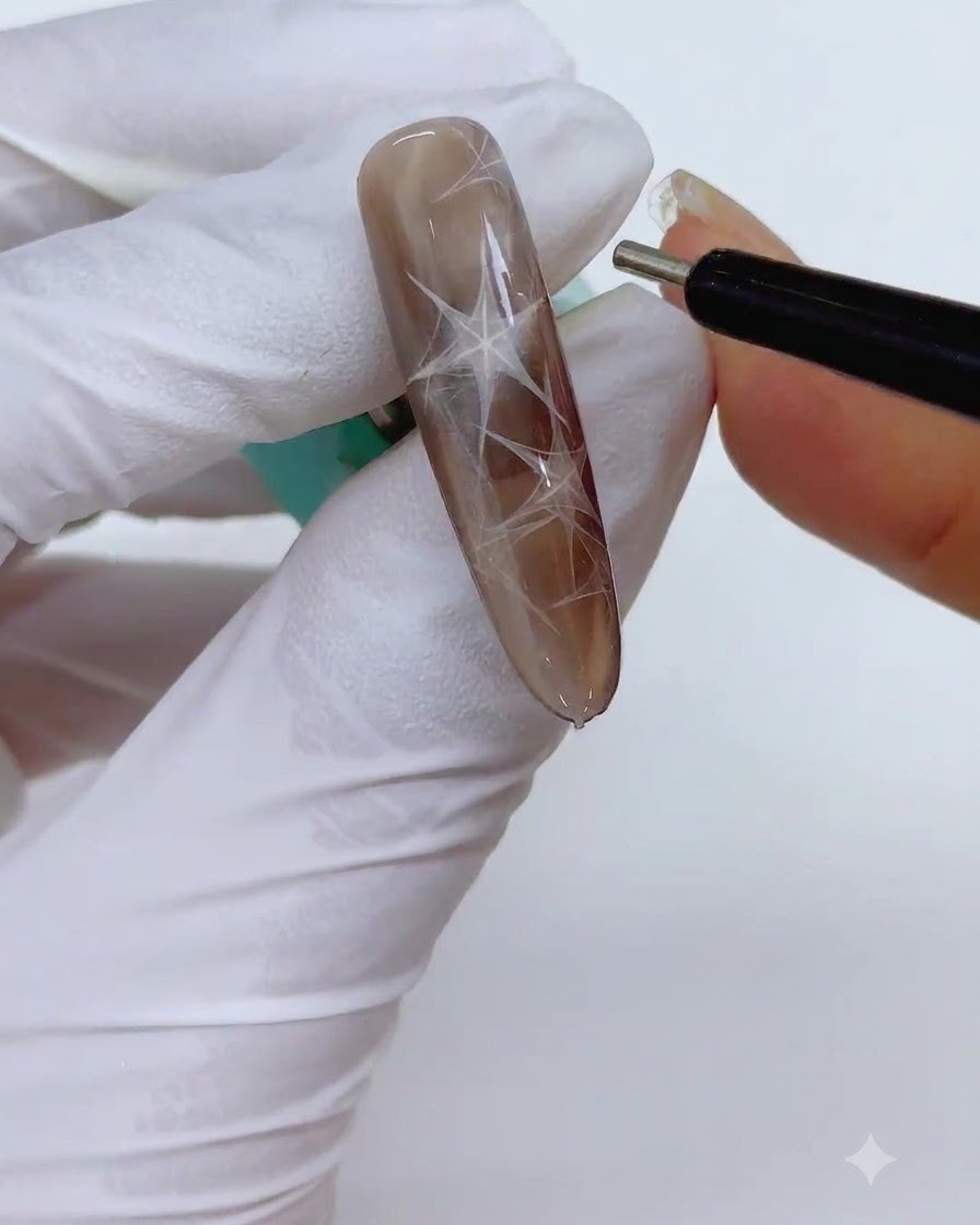Una herramienta de bolígrafo magnético cilíndrico fino sostenida cerca de la uña para afilar los bordes de la forma triangular magnética.