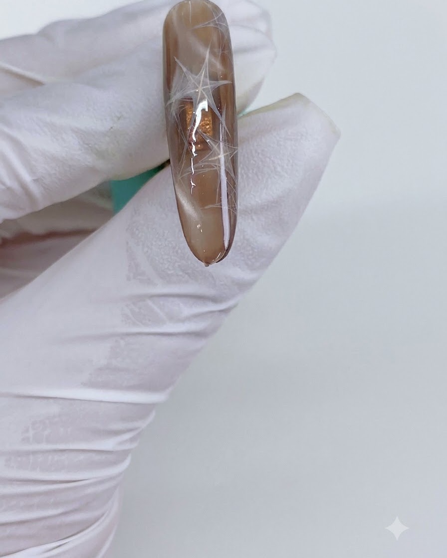 Una uña manicurada con triángulos cat-eye siendo colocada bajo una luz de curado.