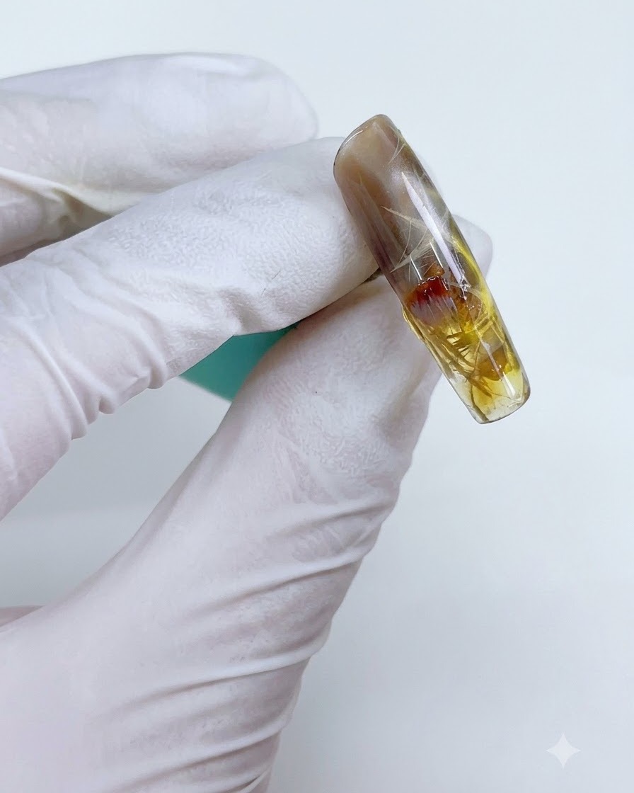 Una uña con gel amarillo-marrón translúcido aplicado selectivamente sobre el diseño estelar.