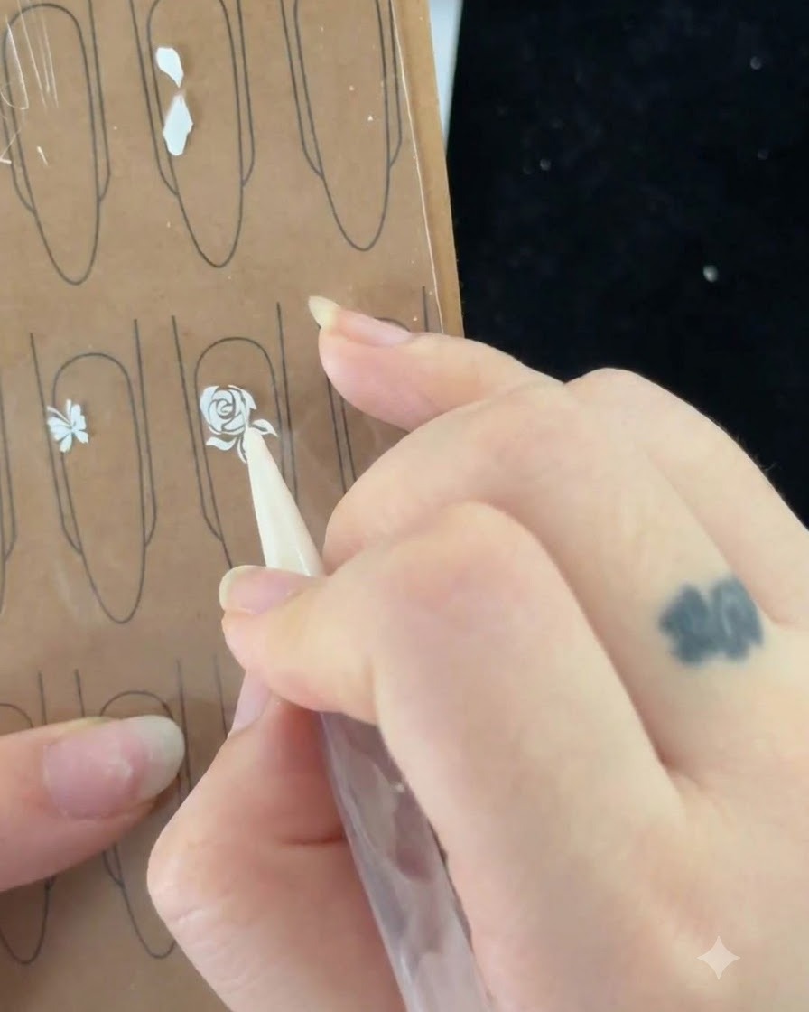 Un pincel de uñas tirando de una línea delgada para comenzar a pintar una hoja al lado de la rosa.