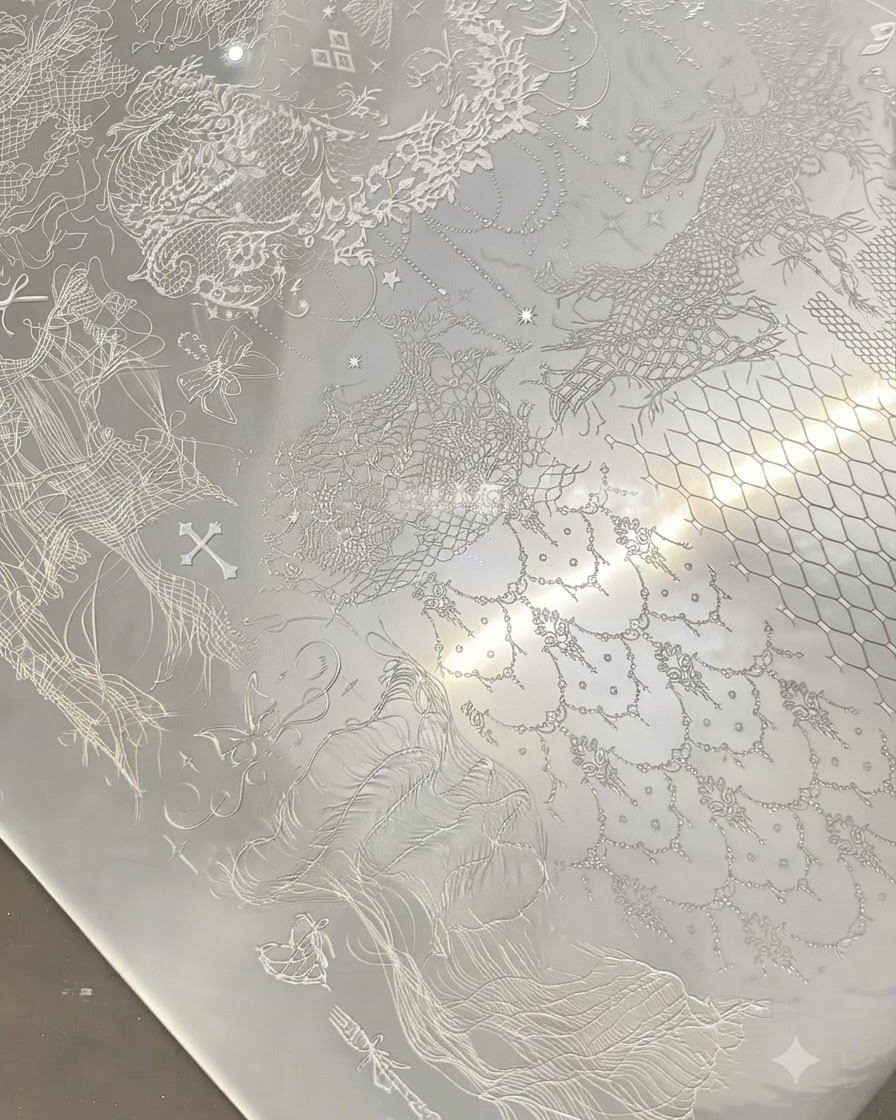 Un estampador transparente presionando sobre una placa de metal con intrincados patrones de encaje blanco.
