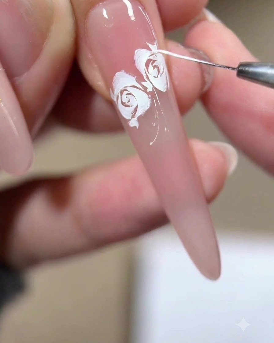 Primer plano de un pincel liner tirando de finos mechones y fragmentos blancos alrededor de los bordes de un diseño de rosa completado.