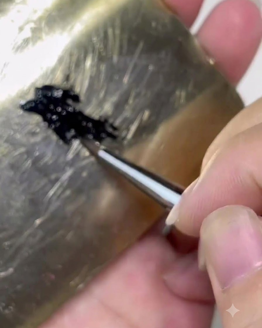 Un pincel cargando producto de gel negro desde una paleta en aproximadamente un tercio del cuerpo del pincel.