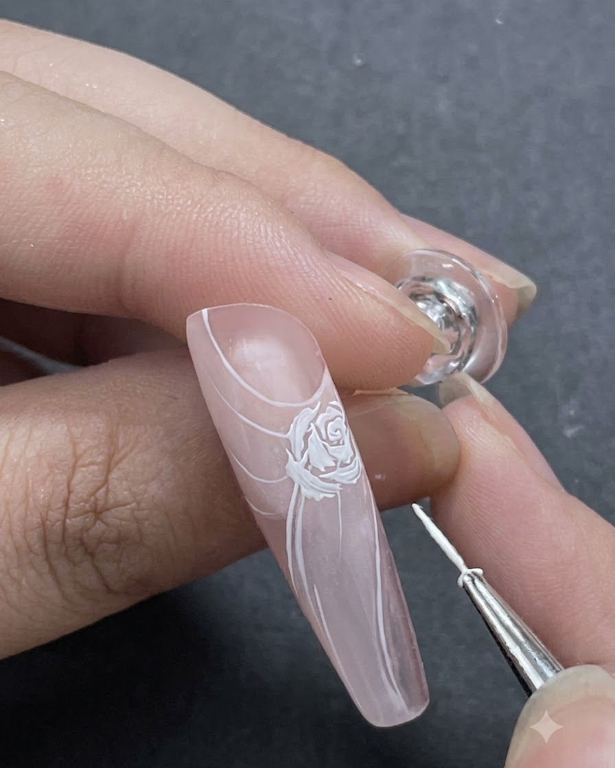 Una toma de cerca que muestra finos acentos de pétalos blancos agregados alrededor del diseño principal de la rosa con un pincel delineador.