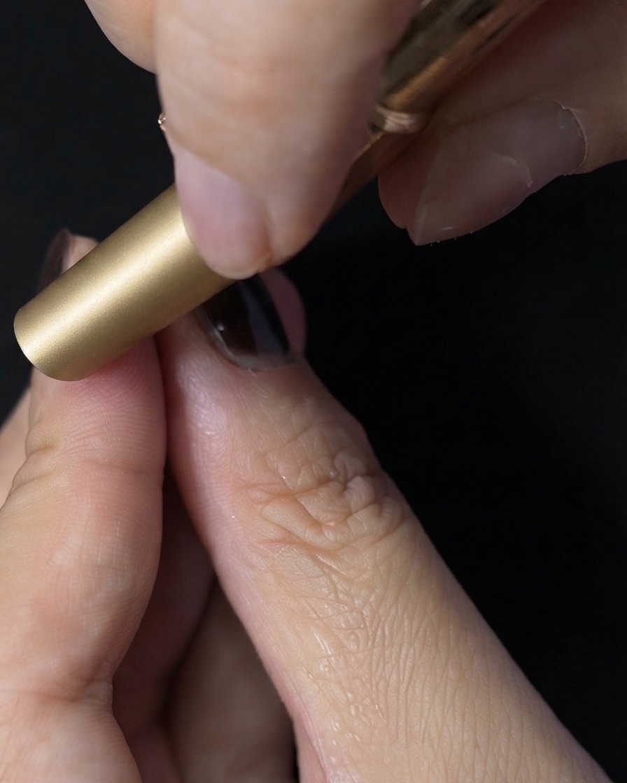 Una uña colocada dentro de una mini lámpara UV LED para curar el top coat.