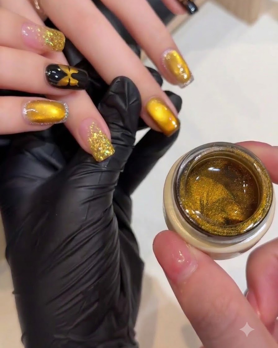 Una manicurista usando una pequeña varita magnética para moldear las partículas brillantes en una uña con efecto ojo de gato dorado.