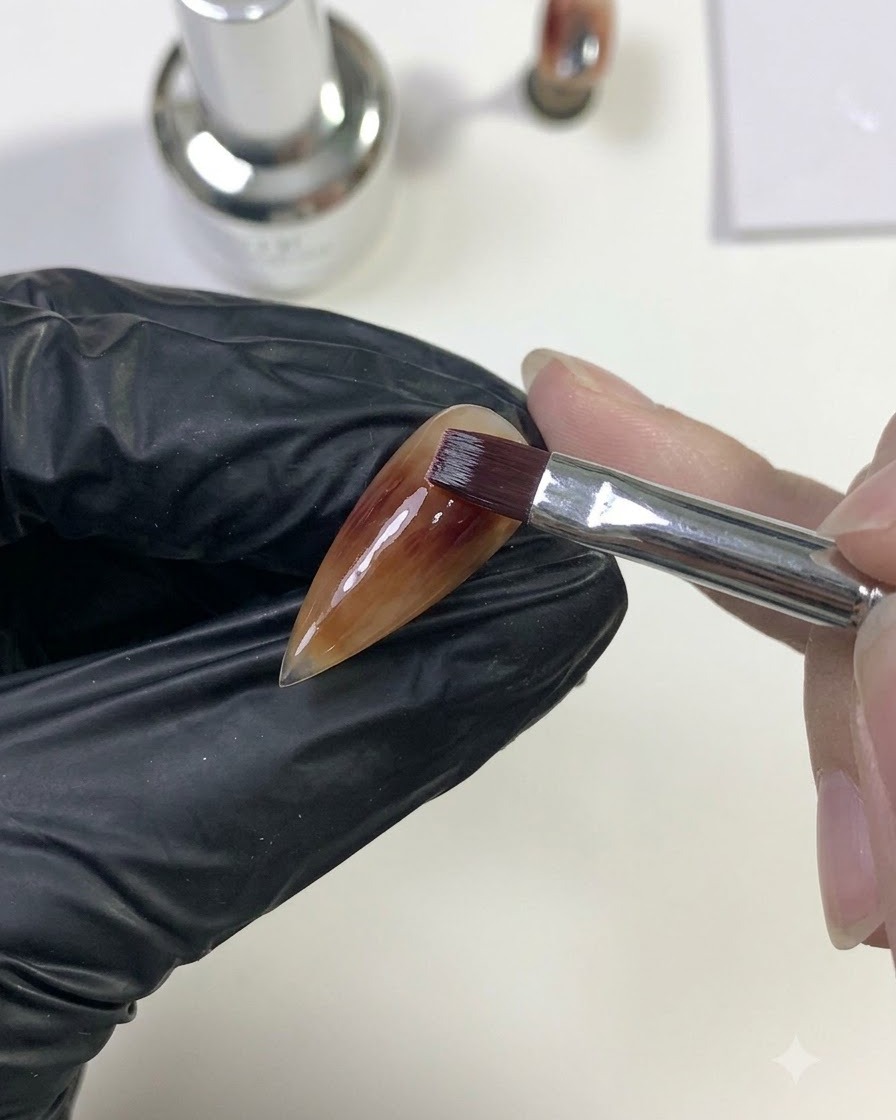 Un pincel mezclando el gel rojo intenso hacia afuera para unirse con la capa base caramelo.