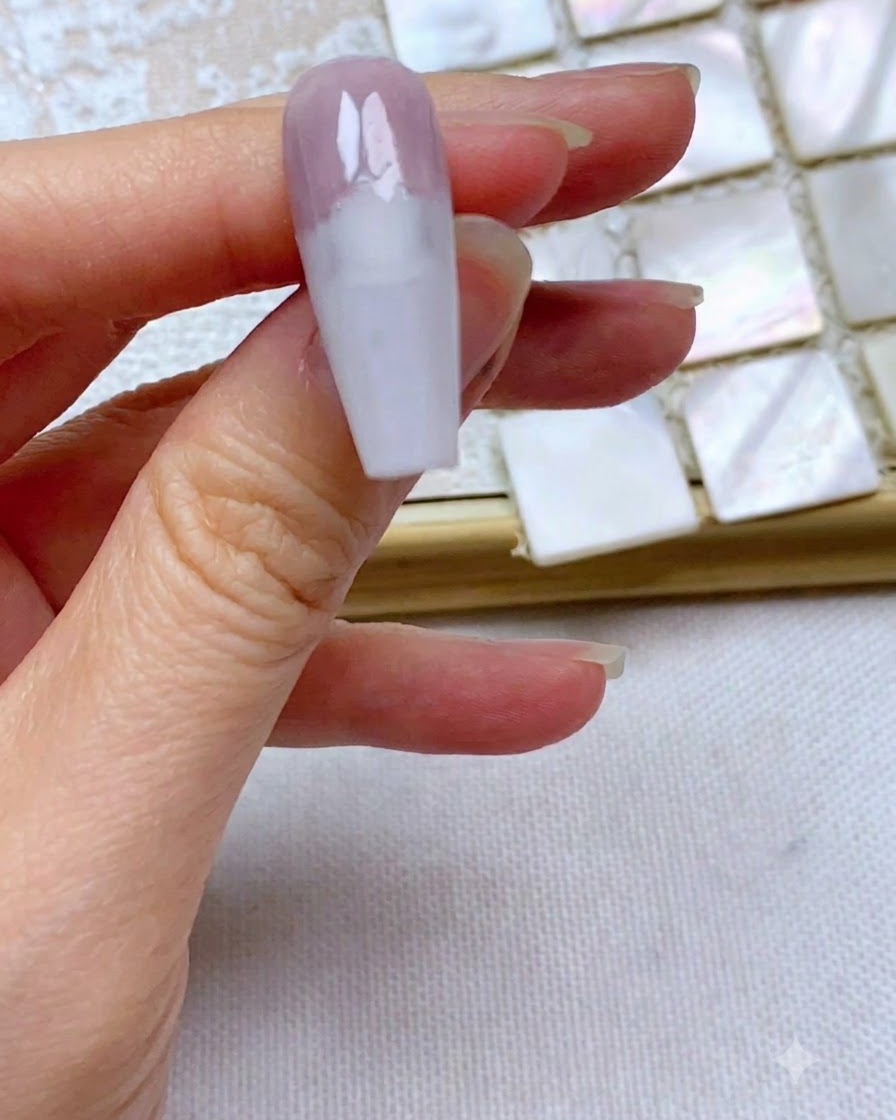 Una uña que muestra un borde de gel gris morado perfectamente recto y limpio aplicado en el tercio superior.