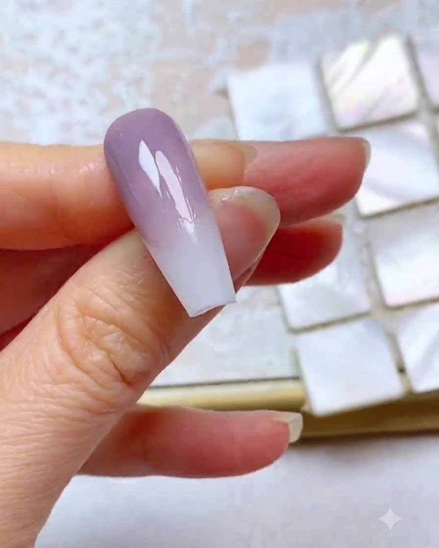Una uña que muestra una tercera capa difuminada de gel morado con un borde superior limpio.