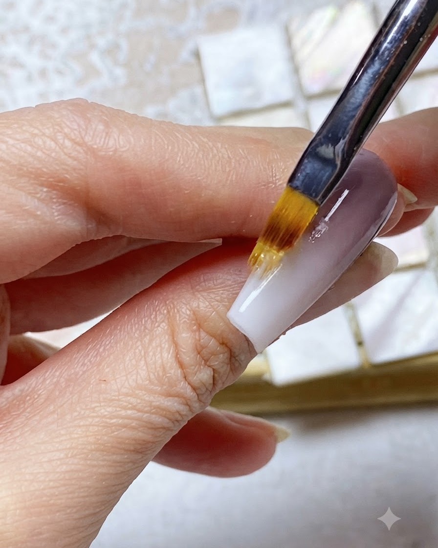 Un pincel ombré difuminando el gel de la punta blanca hacia arriba en la sección superior morada de la uña.