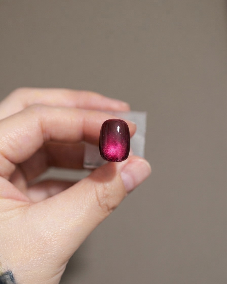 Una uña que muestra una segunda capa de esmalte de gel cat-eye morado oscuro.