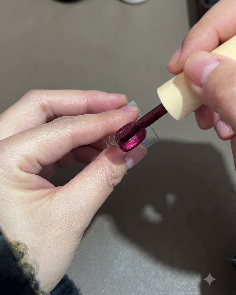 Un pincel alisando una segunda capa de esmalte de gel cat-eye morado en un soporte para uñas.