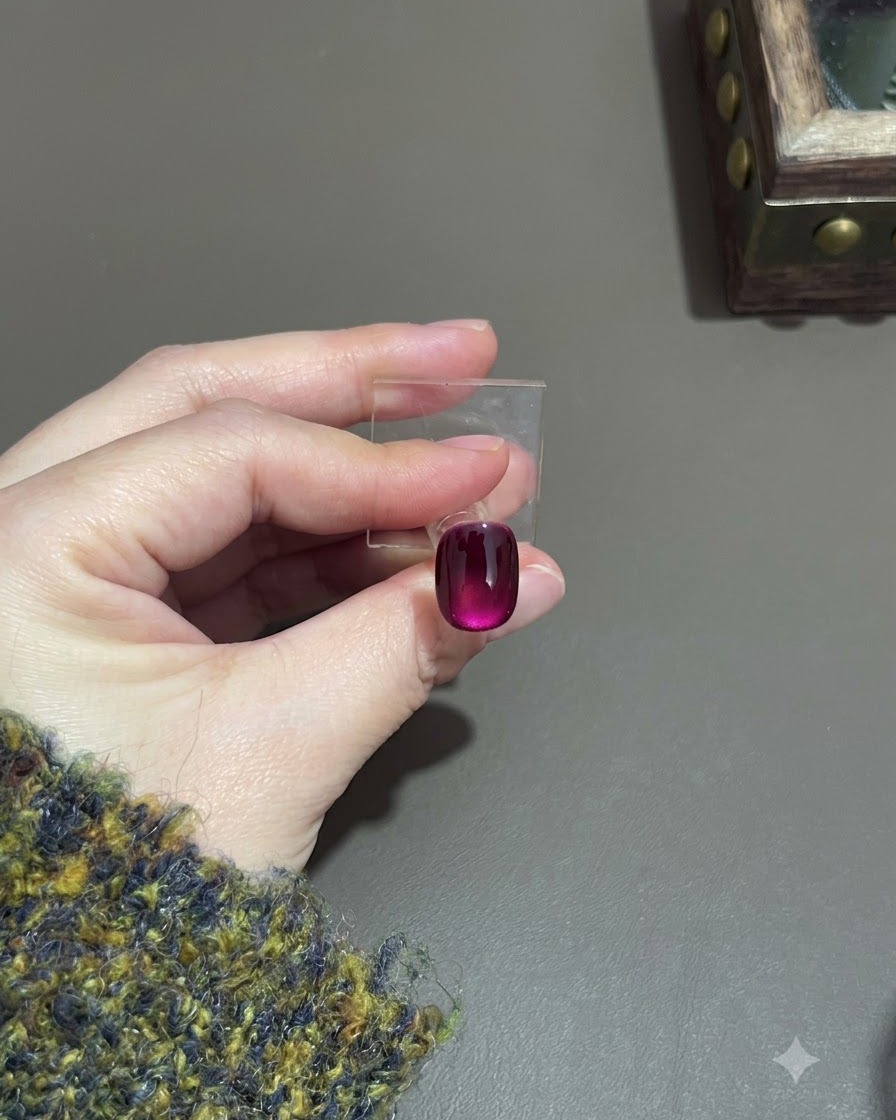 Una uña cat-eye morada curada que muestra un efecto de degradado profundo en un soporte.