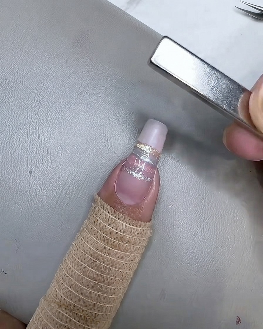 La uña curándose bajo una mini lámpara UV LED después de que la raya cat eye champán ha sido magnetizada.
