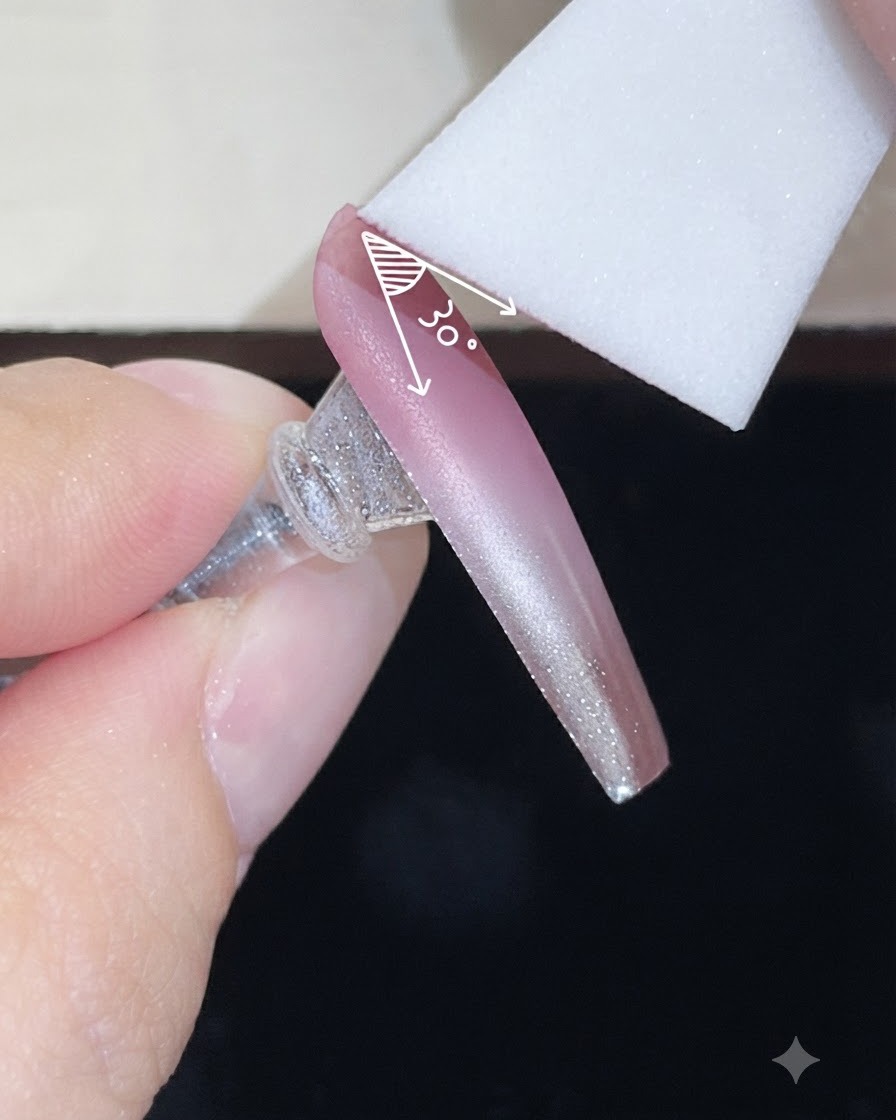 Una esponja de espuma aplicando una segunda capa de gel de color sobre una uña con degradado nude en un ángulo controlado.