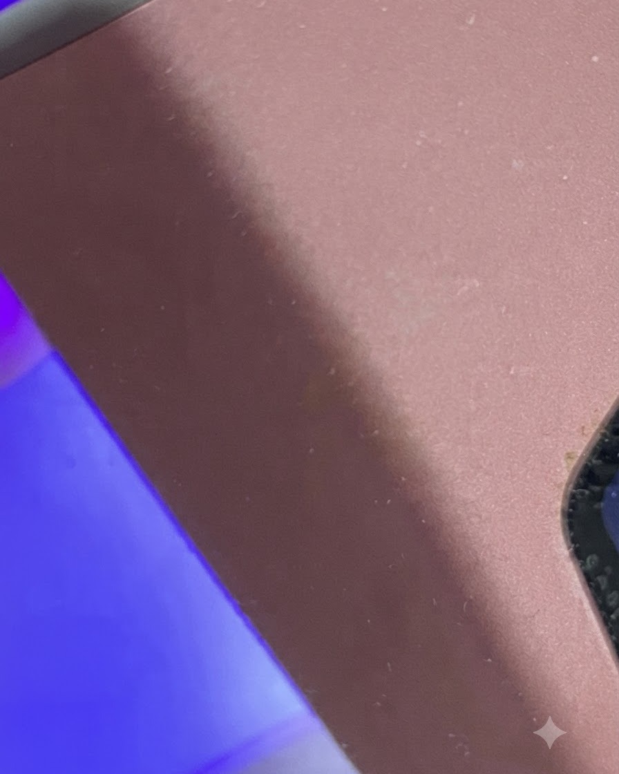 Un dedo colocado bajo una mini lámpara UV/LED con luz púrpura para el curado.