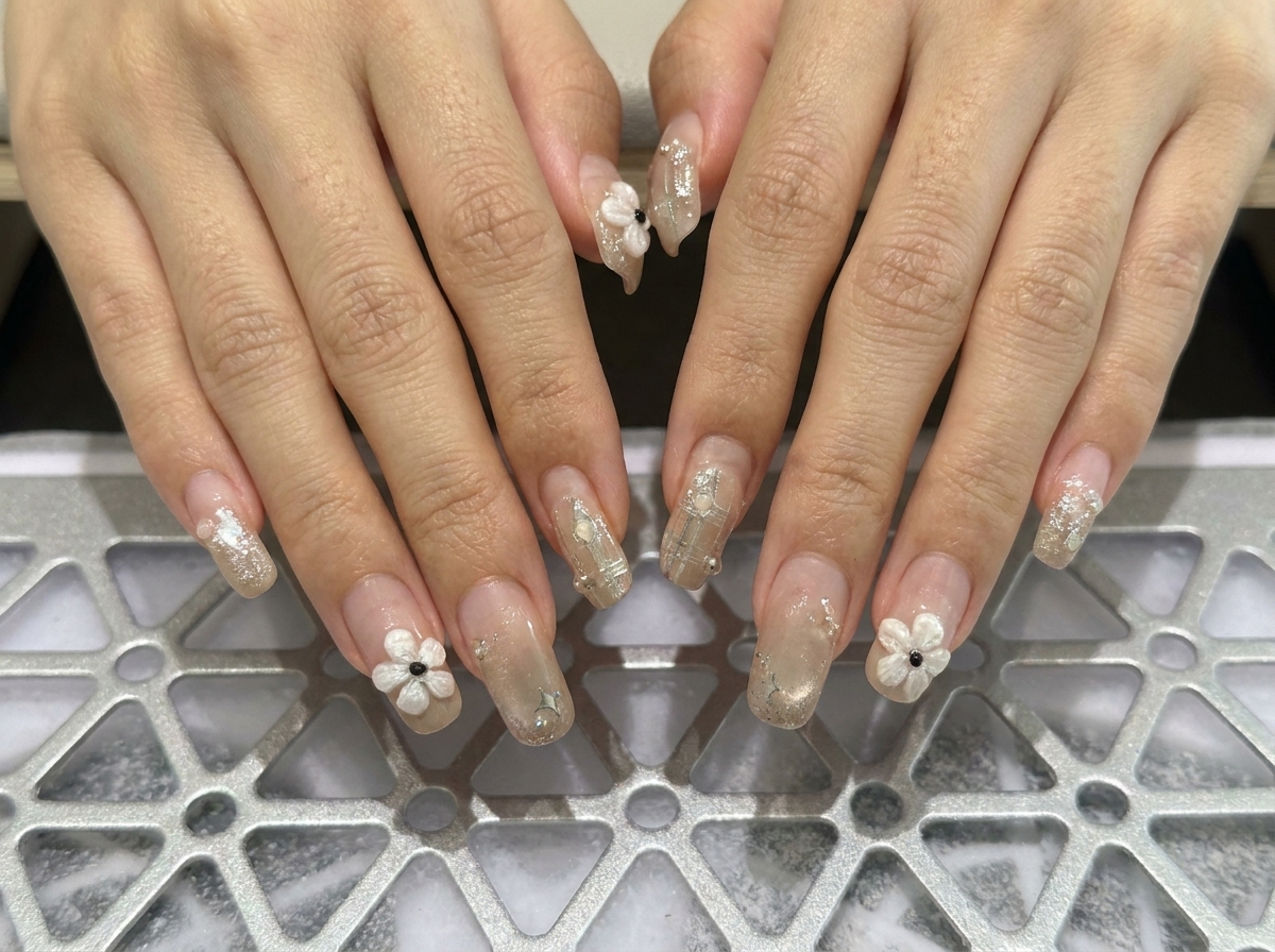 Toma macro enfocada en los dedos de la mano izquierda que muestran uñas cuadradas estructuradas adornadas con delicados acentos de perlas.